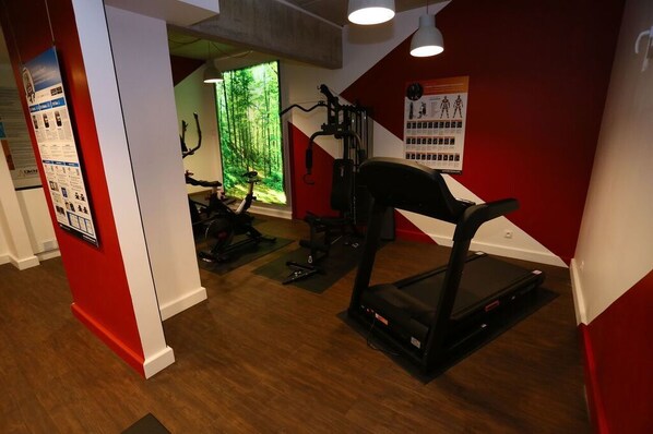 A gym with exercise equipment, a treadmill, and a poster on the wall.