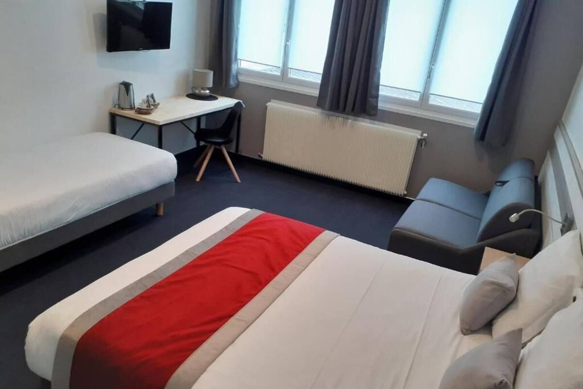 Une chambre d’hôtel avec un lit, un bureau, une chaise et un téléviseur.