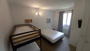 A room with two single beds, a small table, and a window with curtains.