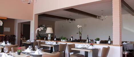 Un ristorante con diversi tavoli, sedie e un'area bar.