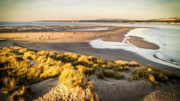 Une plage avec des dunes de sable et un ciel dégagé.