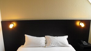 Una habitación de hotel con una cama grande, dos lámparas de noche y un teléfono en la mesita de noche.
