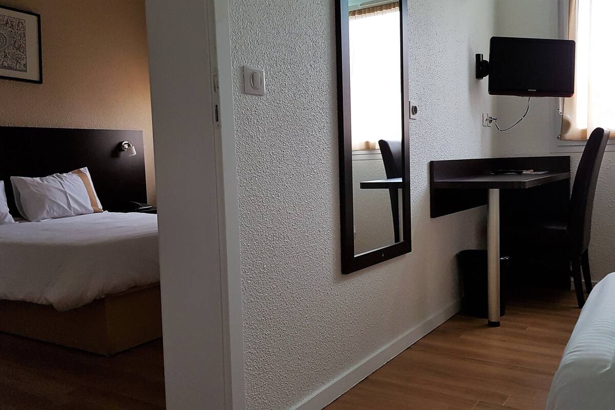 A hotel room with a bed, a desk, and a TV.