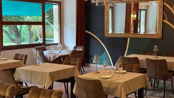 A restaurant with tables set for dining, a chandelier, and a large mirror on the wall.