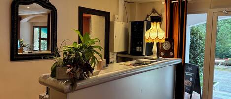 A reception desk with a mirror, a potted plant, a clock, and a lamp.