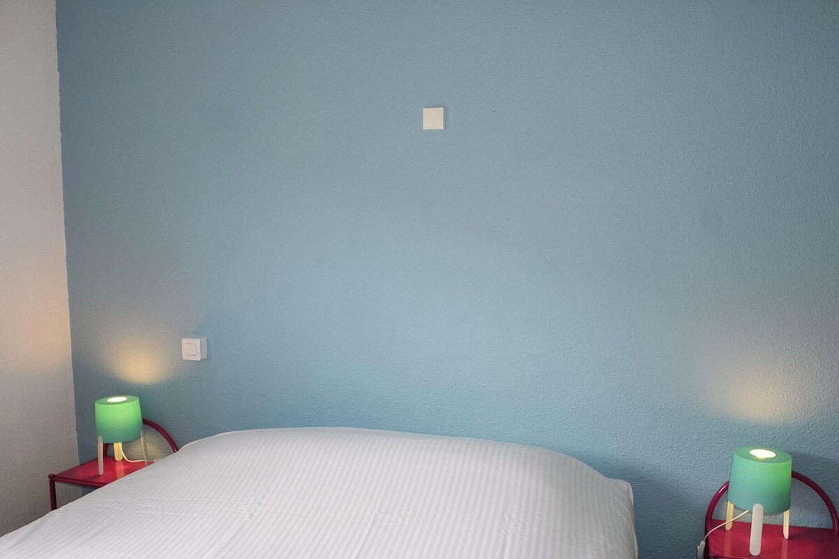 A room with a bed, two nightstands, and two wall-mounted lamps.