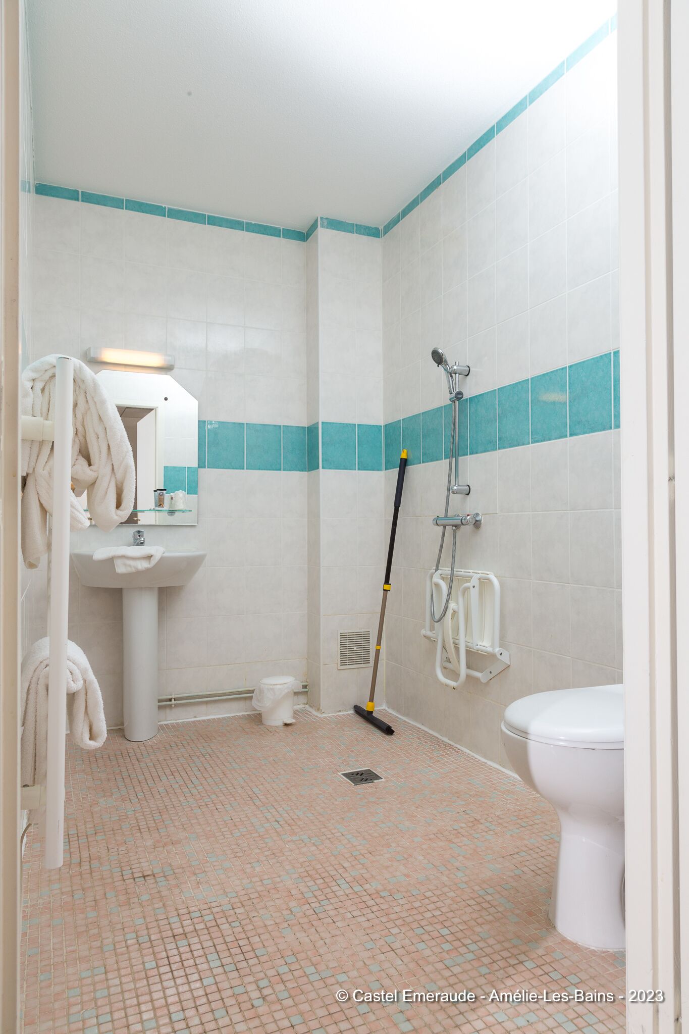 A bathroom with a sink, mirror, towel rack, shower, and toilet.