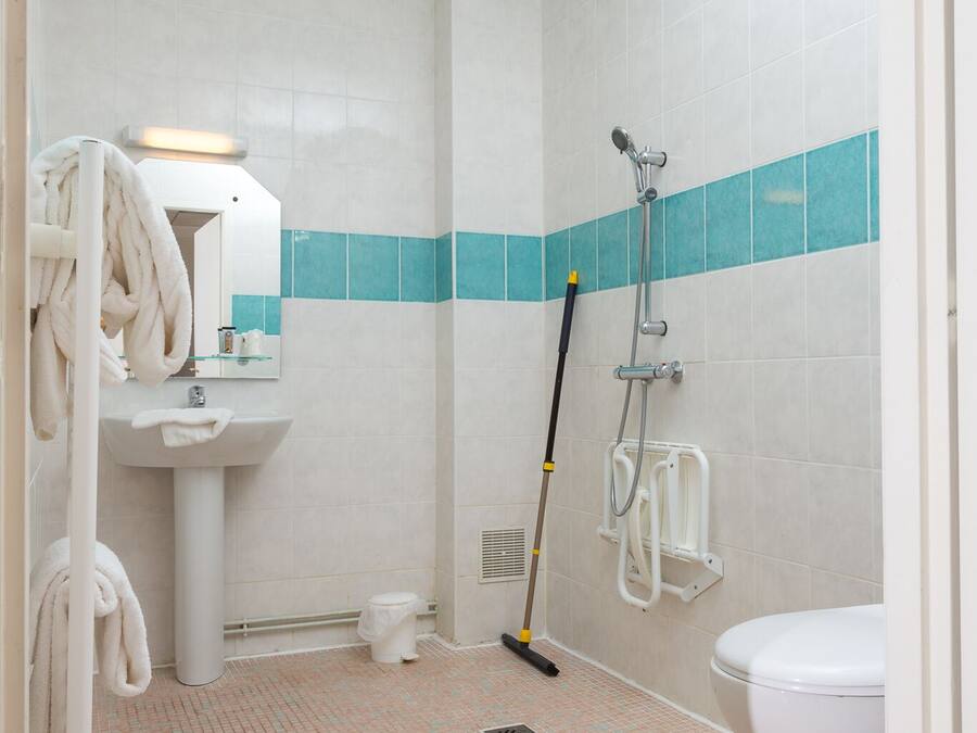 A bathroom with a sink, mirror, towel rack, shower, and toilet.