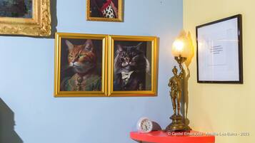 A wall with framed pictures of cats and a statue.