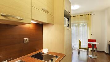 A compact kitchen with a built-in stove, a sink, and wooden cabinets. There is a small dining area with a table and two chairs.