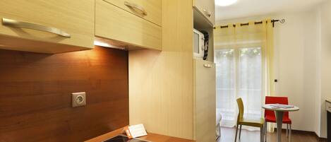 A compact kitchen with a built-in stove, a sink, and wooden cabinets. There is a small dining area with a table and two chairs.