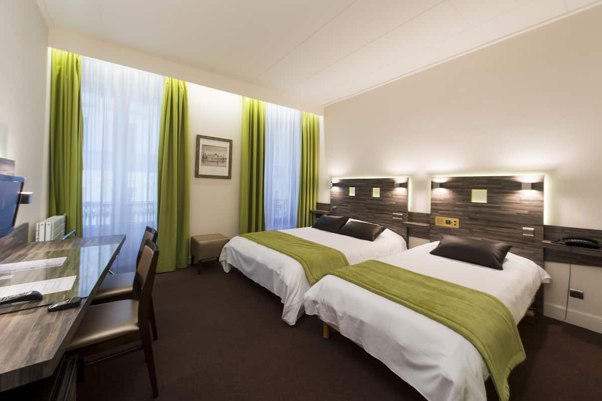 Una habitación de hotel con dos camas, un escritorio y una silla.