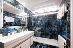 Un baño moderno con un espejo grande, dos lavamanos y una zona de ducha.
