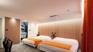 A hotel room with two beds, a desk, and a bathroom visible through a sliding door. - Hôtel La Résidence Lyon (Lyon)