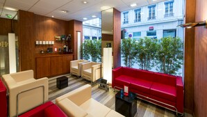 A modern hotel lobby with a red sofa, beige armchairs, and a reception desk. - Hôtel La Résidence Lyon (Lyon)