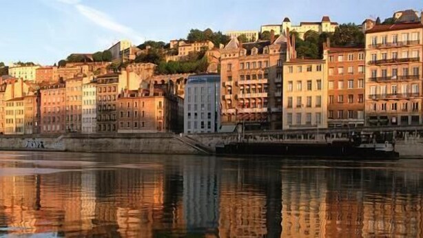 A riverside cityscape with historic buildings and a prominent church. - Hôtel La Résidence Lyon (Lyon)