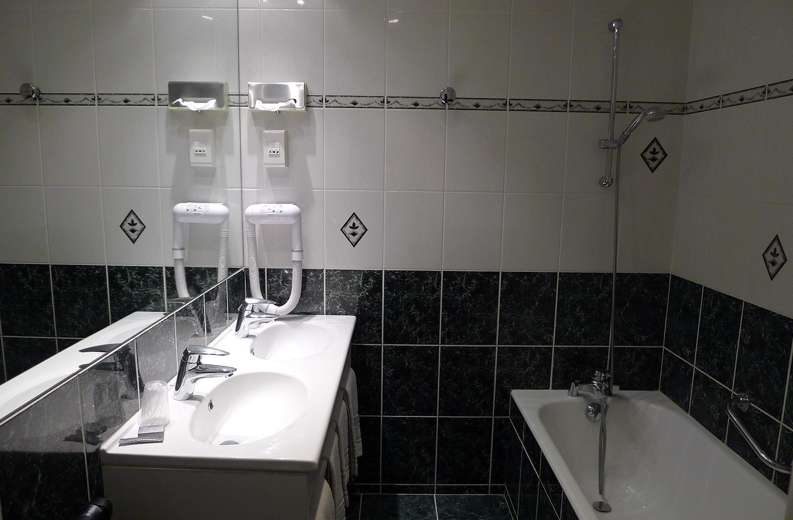 A modern bathroom with a white sink, a mirror, a handheld showerhead, and a bathtub.