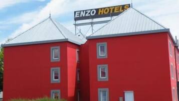 A red building with a sign that reads "ENZO HOTELS" on the roof.
