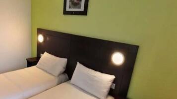 A double bed with white bedding and a dark headboard, two bedside tables, and a framed picture on the wall.