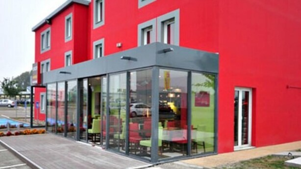 A modern building with a red facade and a glass extension. - Enzo Hotels Mulhouse Sud Morschwiller (Morschwiller-le-Bas)