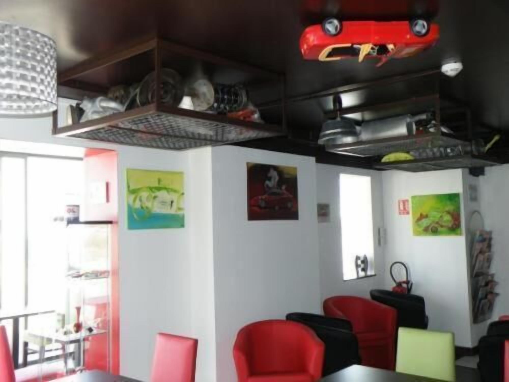 A dining area with red and black chairs, a table, and a ceiling with a red car model.