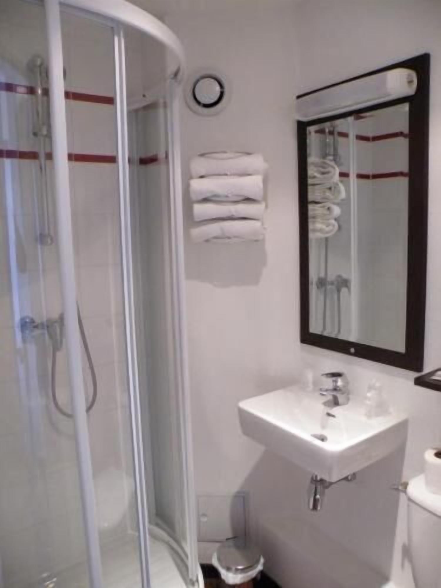 A bathroom with a glass-enclosed shower, a sink, and a toilet.