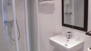 A bathroom with a glass-enclosed shower, a sink, and a toilet.