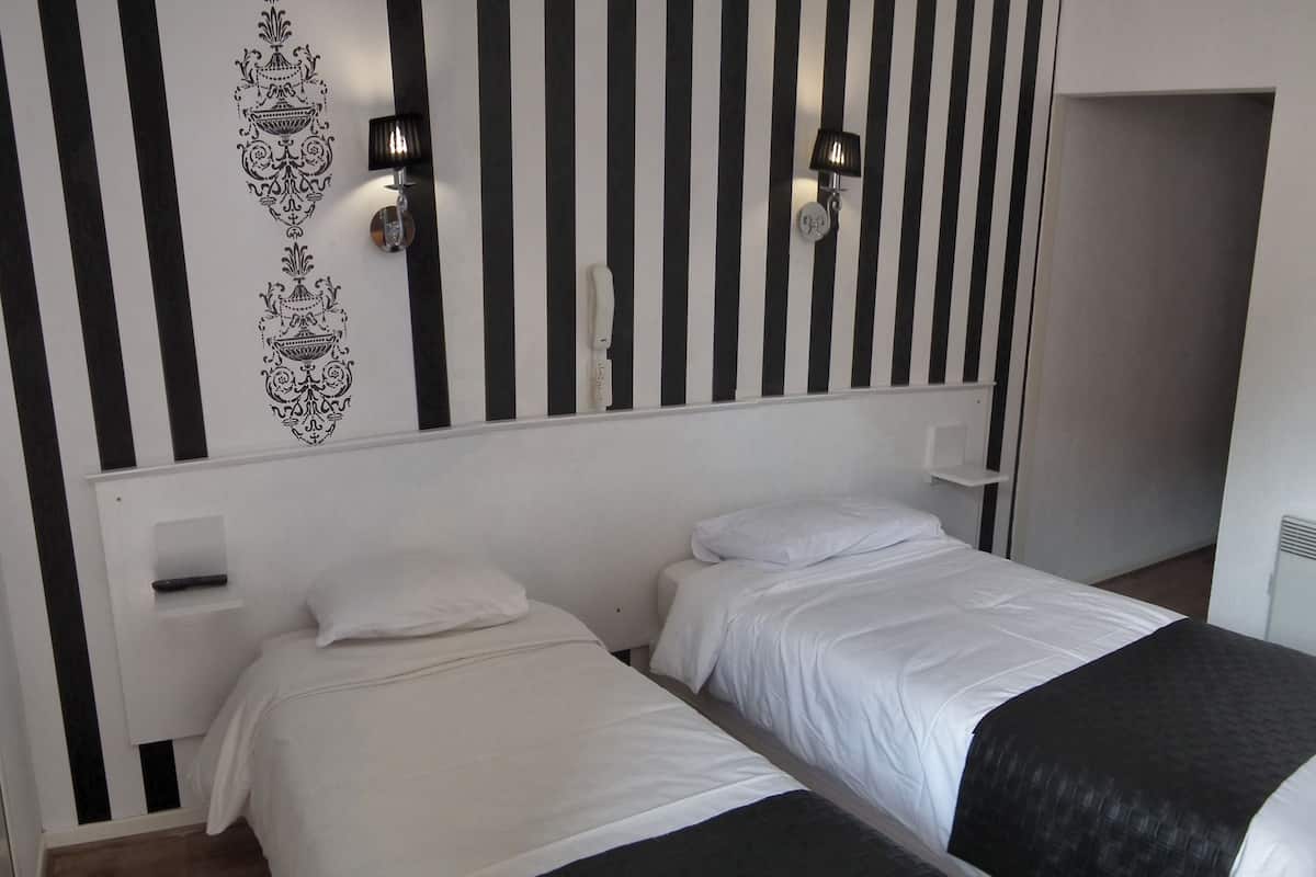 A hotel room with two beds, a striped wall, and two wall-mounted lamps.