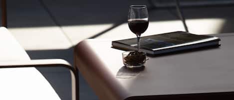 A modern outdoor seating area with a table and chairs, a glass of red wine, and a book.