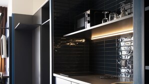 A modern kitchen with dark cabinetry, a stainless steel sink, and a patterned floor. - Hôtel Le Bugatti (Molsheim)
