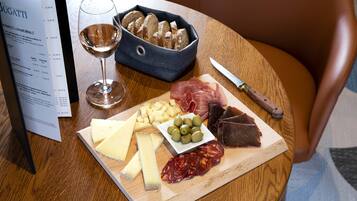A wooden table with a cheese board, a bottle of wine, and a menu.