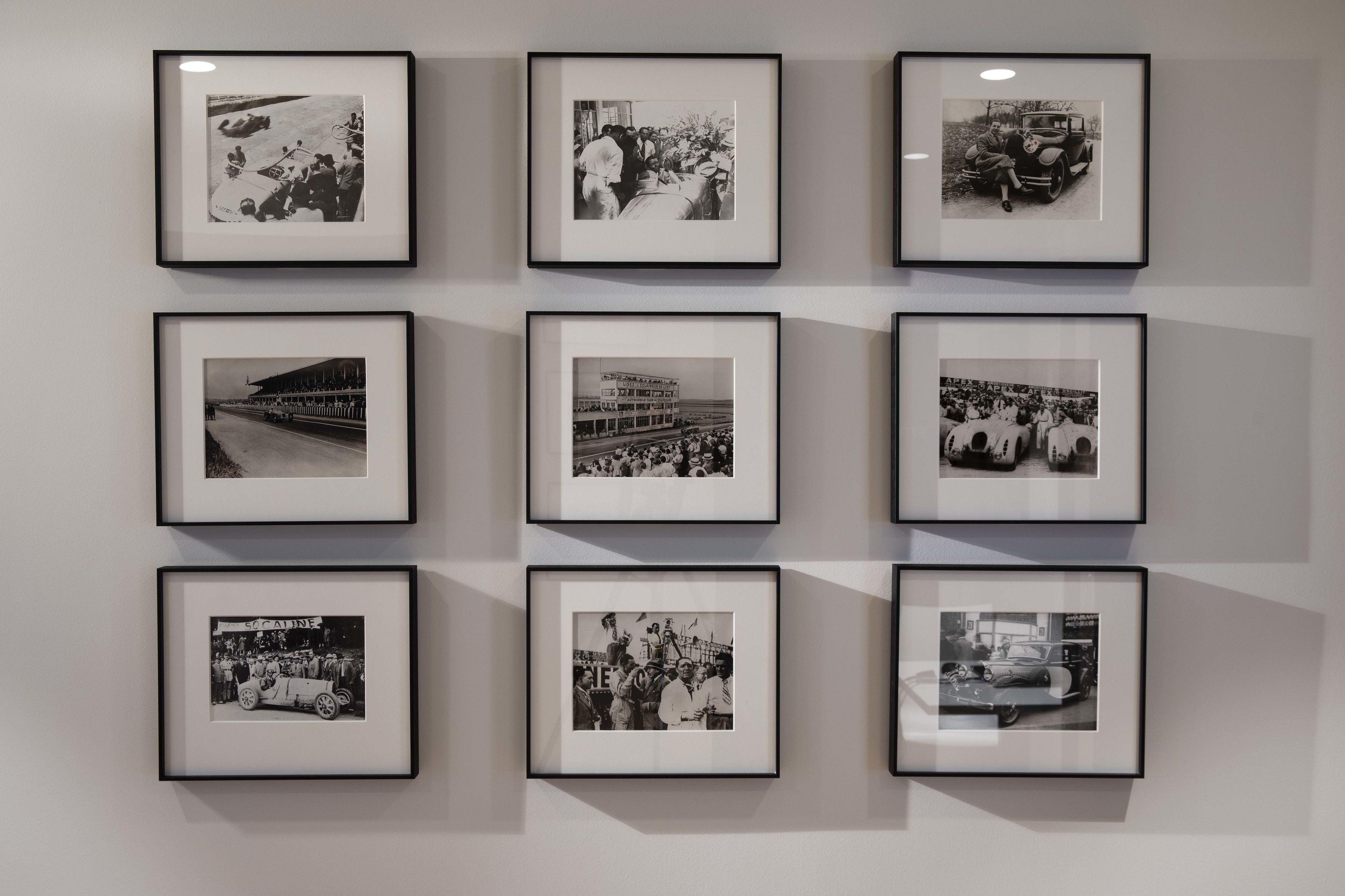 Pared con nueve fotografías en blanco y negro enmarcadas, dispuestas en una cuadrícula de 3x3.