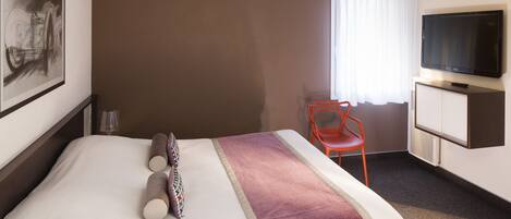 Una habitación de hotel con una cama, un televisor, una silla y un cuadro en la pared.