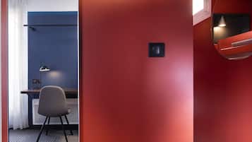 Una habitación con una pared roja, un escritorio con una silla y una cama con cabecera.