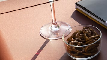 A glass of red wine and a bowl of pretzels on a table.