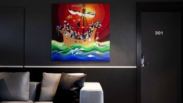 Una habitación moderna con un cuadro grande de un barco en la pared, un sofá gris y una puerta con la etiqueta 301.