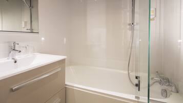 Een moderne badkamer met een glazen douchecabine, een wit wastafelmeubel en een spiegel erboven.