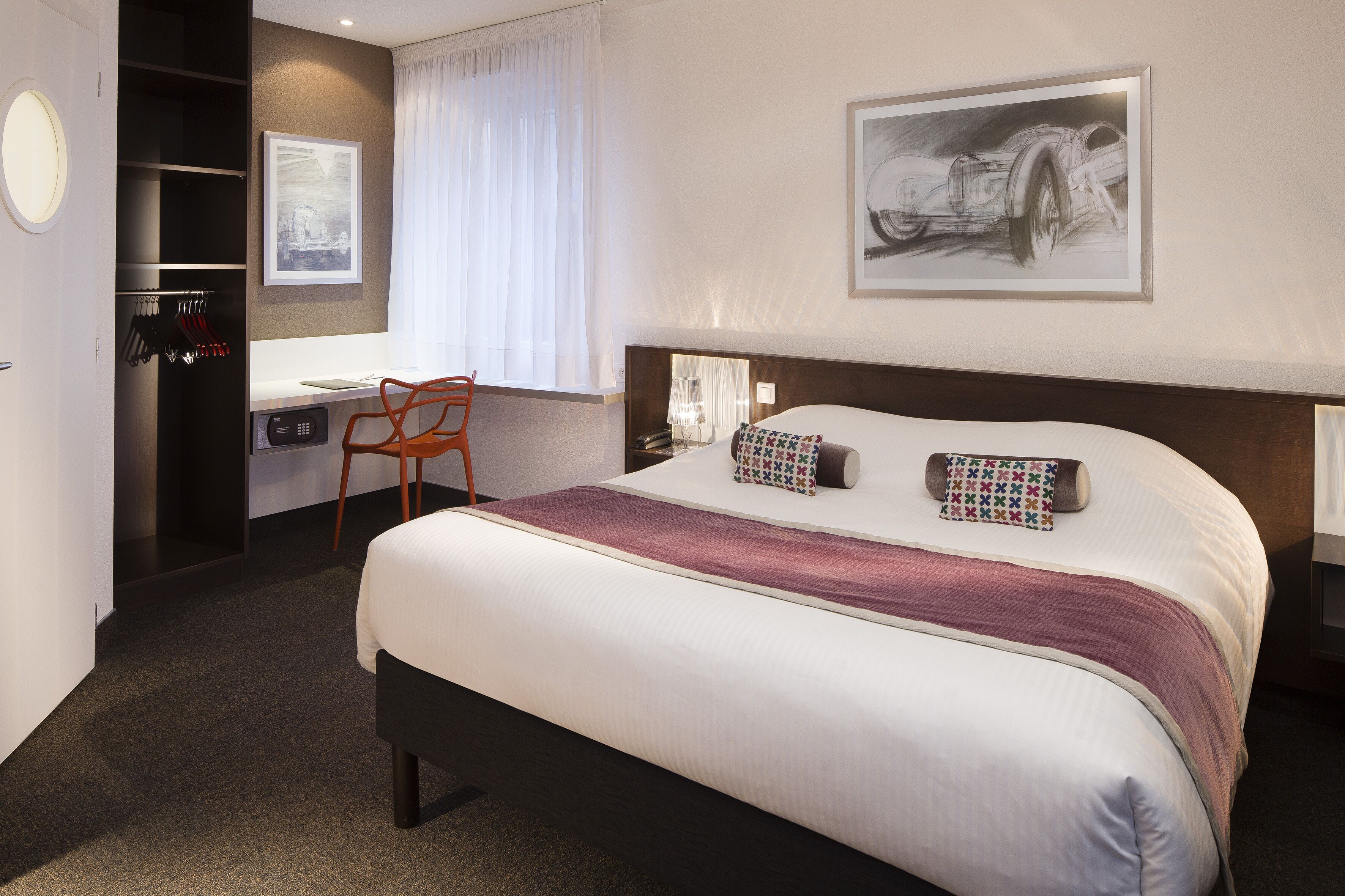 A hotel room with a large bed, a desk, and a chair.