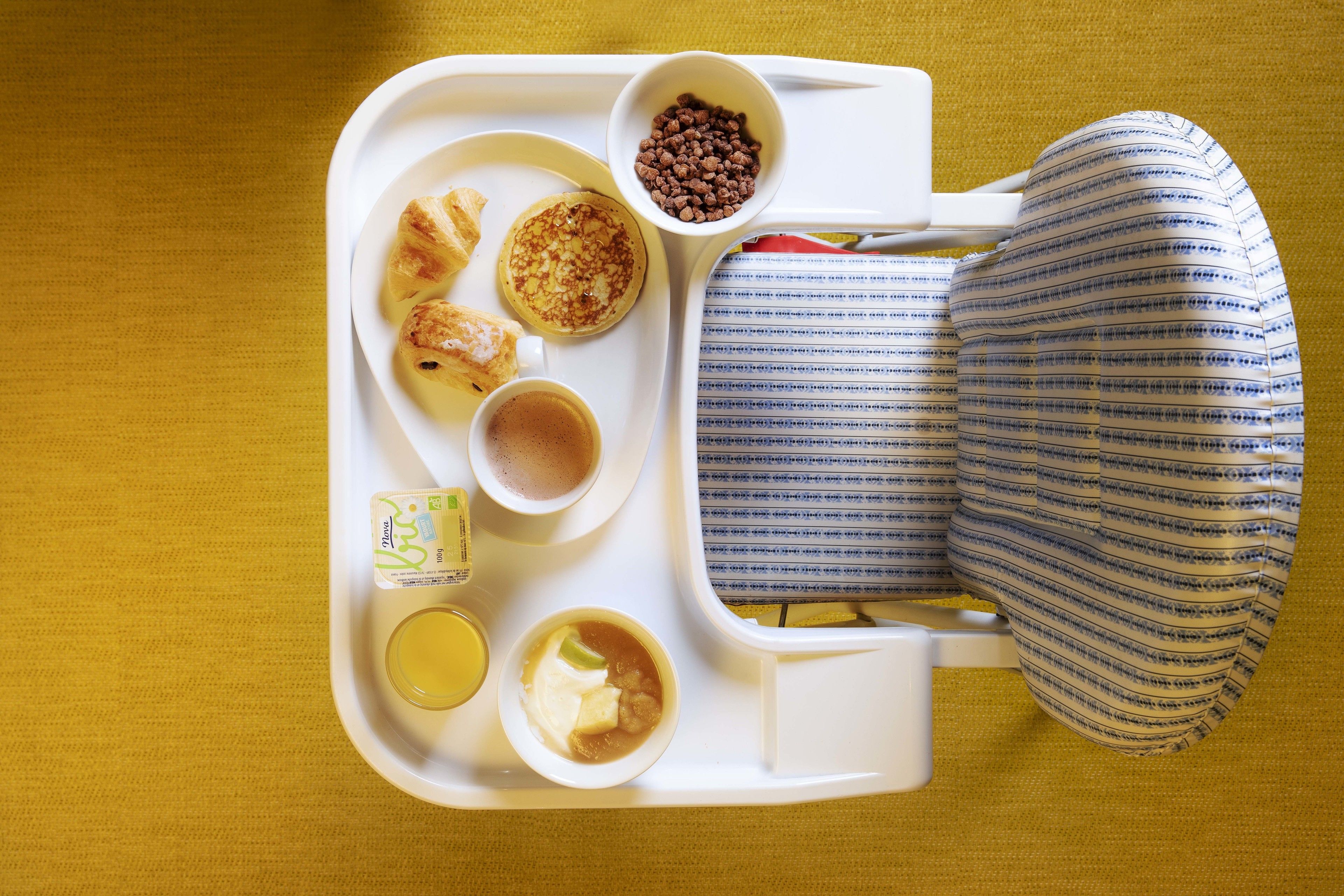 A tray with food items including pancakes, a cup of coffee, and a bowl of cereal.