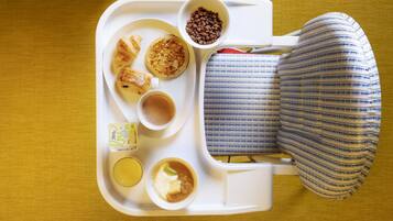 A tray with food items including pancakes, a cup of coffee, and a bowl of cereal.