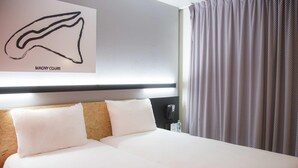A hotel room with a large bed, two pillows, a headboard, a wall-mounted phone, and a curtain. - ibis Styles Bâle-Mulhouse Aéroport (Blotzheim)