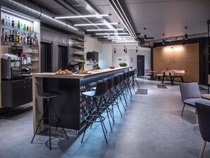 Zona de bar moderna con una barra larga, taburetes y una variedad de botellas en estantes.