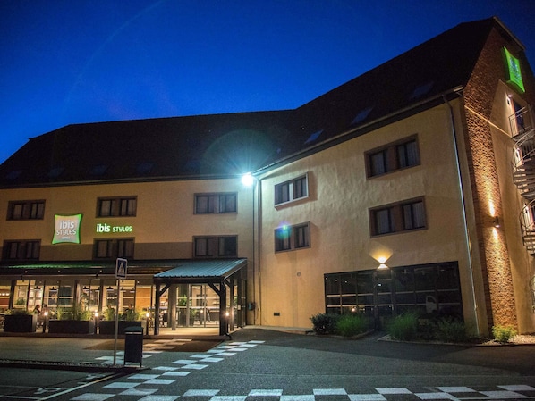 A hotel with a modern design, featuring a covered entrance and multiple windows.