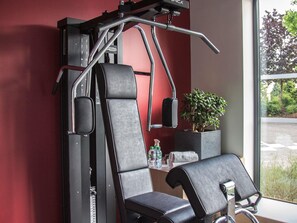 Un gimnasio con equipo de ejercicio, una planta en maceta y un ventanal con vistas.