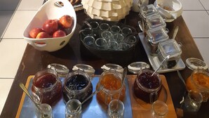 Une table à manger avec divers plats et condiments, une horloge au mur et un coin cuisine en arrière-plan.