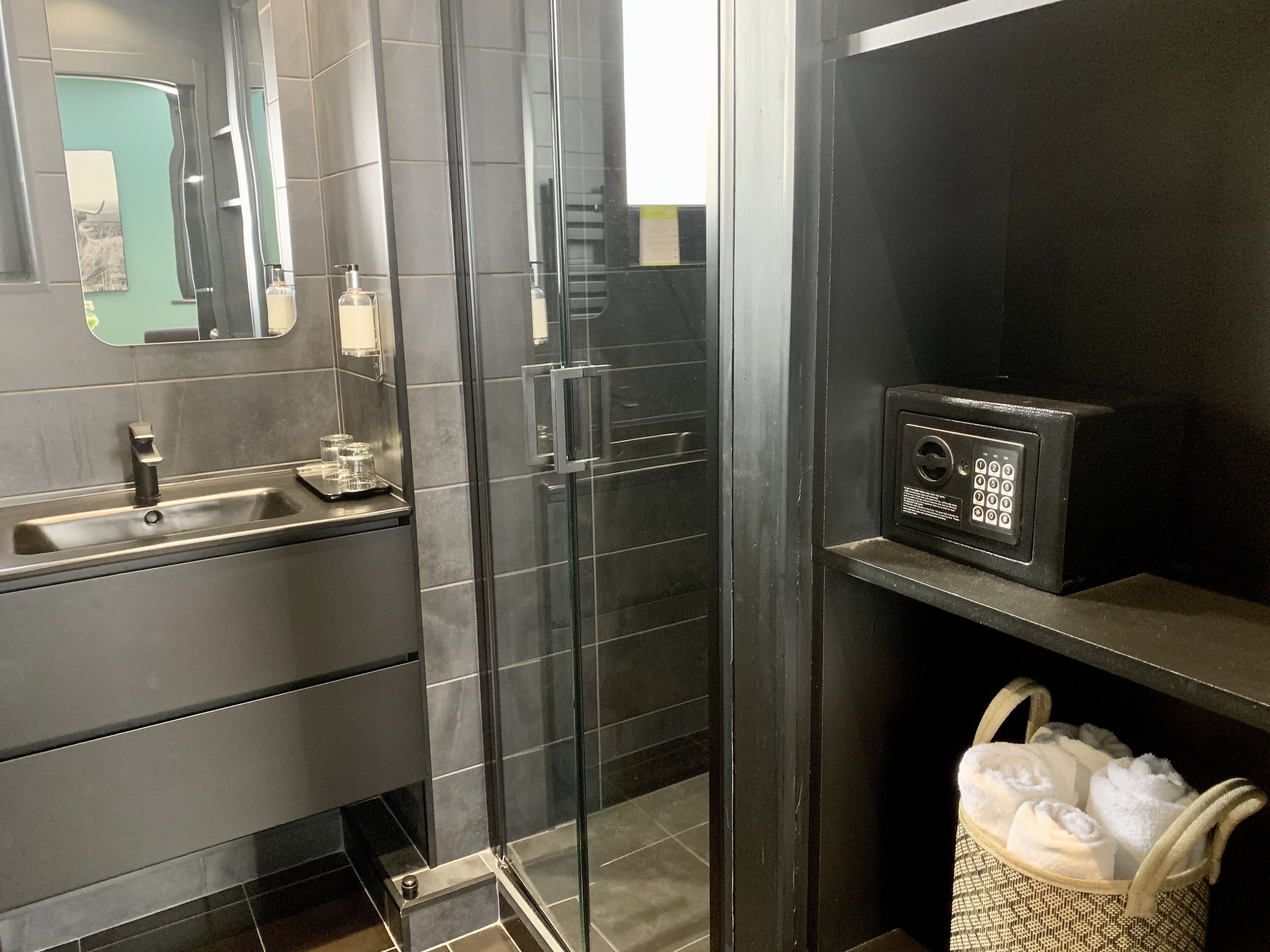 Une salle de bain moderne avec une douche à parois de verre, un lavabo doté d’un distributeur de savon et un porte-serviettes avec des serviettes.