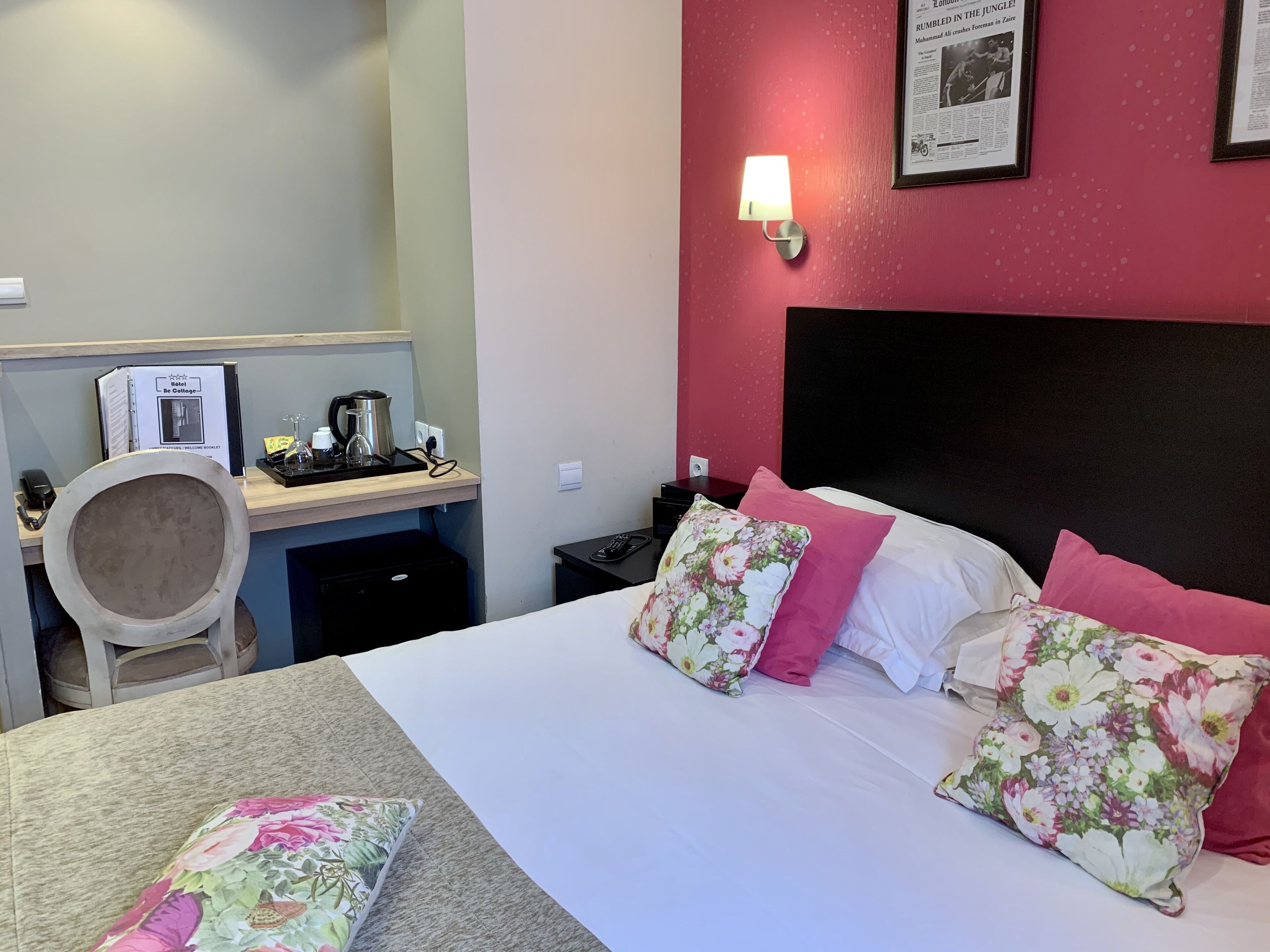 A hotel room with a bed, a desk with a computer, a chair, and a nightstand.