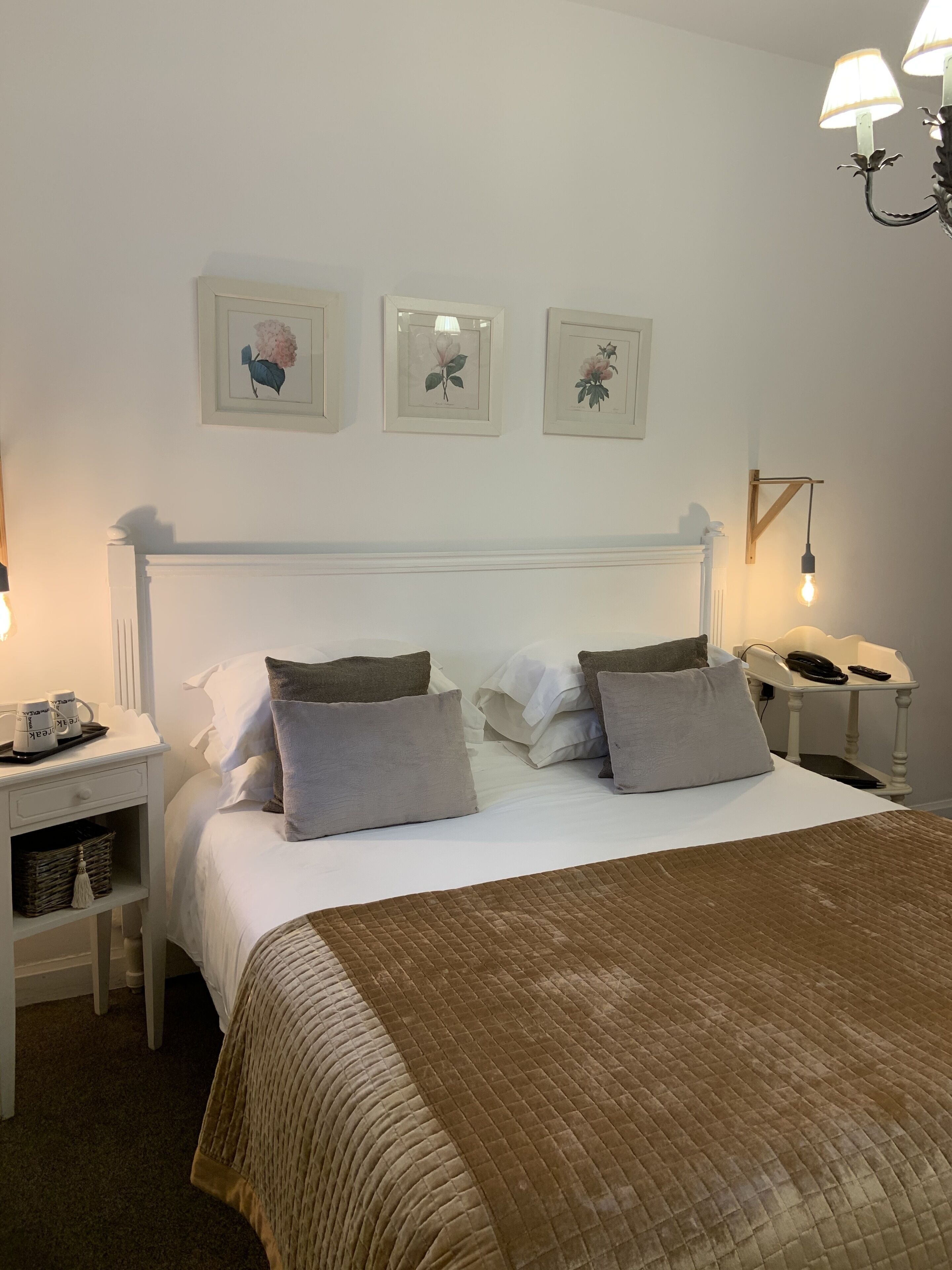 A neatly arranged bedroom with a large bed, bedside tables, and wall-mounted lamps.