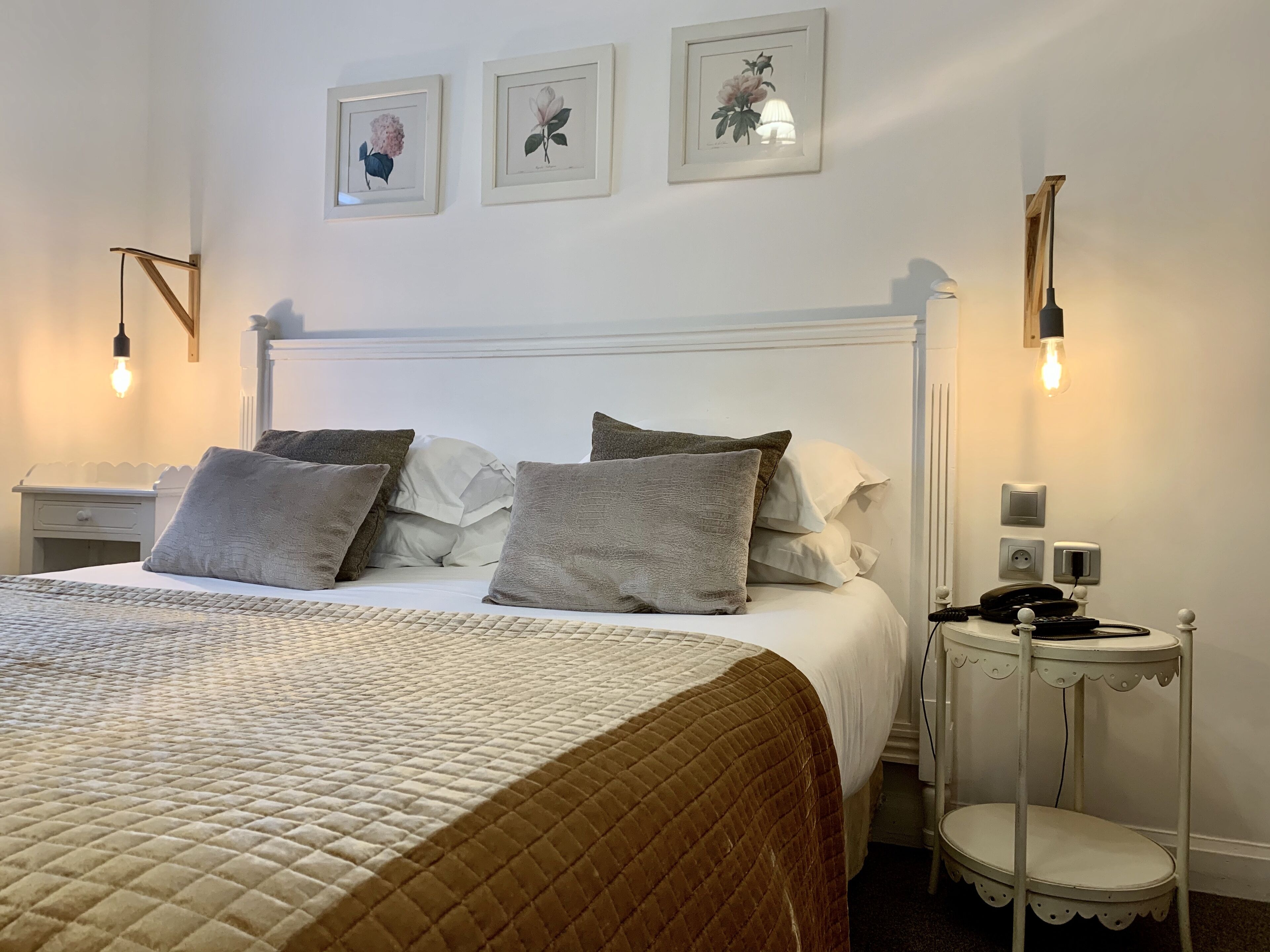 A neatly arranged bedroom with a bed, bedside tables, and wall-mounted light fixtures.