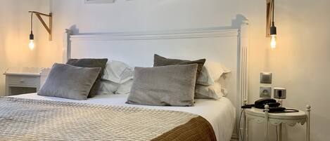 A neatly arranged bedroom with a bed, bedside tables, and wall-mounted light fixtures.